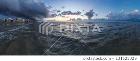 A Serene Ocean Sunset with Dramatic and Colorful Clouds in the Evening Sky Above the Horizon 131523329