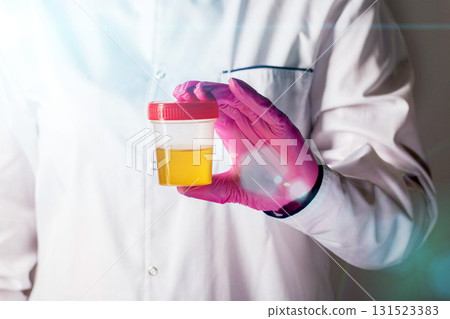 A doctor urologist holds a urine test in his hand in a pink glove, close-up. Cognition of diseases and infections in urology. Copy space for text A doctor urologist holds a urine test in his hand in a pink glove, close-up. Cognition of diseases and infections in urology. Copy space for text 131523383