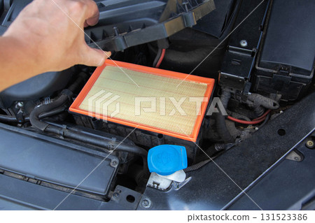 Installing a new clean air filter in the engine compartment of a car to clean the air in the car engine, close-up Installing a new clean air filter in the engine compartment of a car to clean the air in the car engine, close-up 131523386