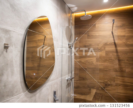 Modern bathroom with a wall made of brown wood tiles, a stylish mirror and a stretch ceiling with a yellow LED strip. Copy space for text 131523456