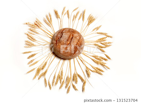 Freshly baked round bread surrounded by golden wheat stalks on a white background Freshly baked round bread surrounded by golden wheat stalks on a white background 131523704