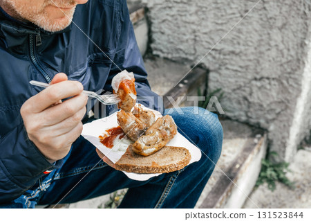 enjoying street food with a savory dish on pleasant day in busy urban area. closeup. 131523844
