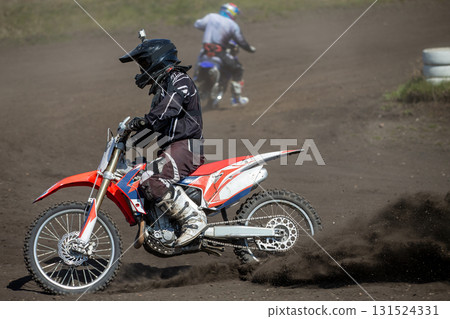 Motocross rider perform turn on track. Dust and dirt from under rear wheel 131524331