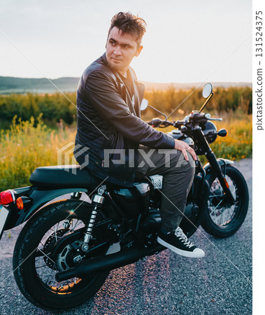 Stylish young man sitting on black vintage motorcycle outdoors Stylish young man sitting on black vintage motorcycle outdoors 131524375