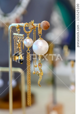 A collection of handcrafted earrings on a gold-plated jewelry stand 131525100
