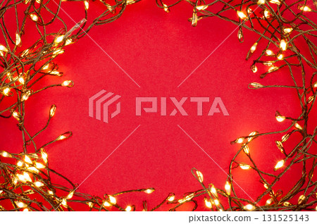 Christmas string lights glowing on red background, festive holiday garland decoration, top view celebration concept 131525143