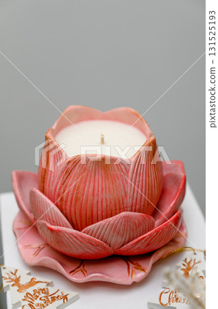 Pink lotus flower shaped candle standing on white background 131525193