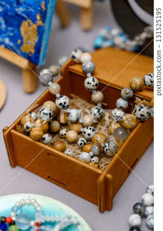 A set of bracelets made of natural stones in an open wooden box at a fair. 131525195
