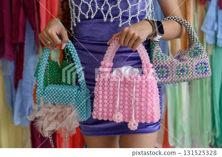 Bright handmade beaded bags with feathers in the hands of the model Bright handmade beaded bags with feathers in the hands of the model 131525328