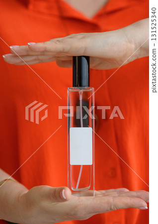 A person holds a transparent bottle of perfume 131525340