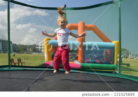A girl in fuchsia pants jumping on a trampoline A girl in fuchsia pants jumping on a trampoline 131525695