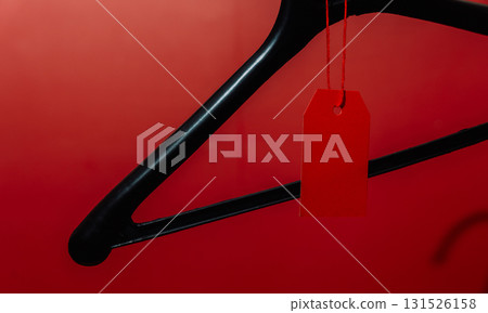 Black hanger with red price tag on red background 131526158