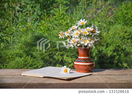 Camomiles in the vase and book Camomiles in the vase and book 131526618