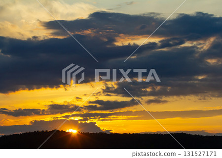 Evening sunset over hills with vibrant clouds and warm hues in the sky during early evening in a tranquil landscape Evening sunset over hills with vibrant clouds and warm hues in the sky during early evening in a tranquil landscape 131527171