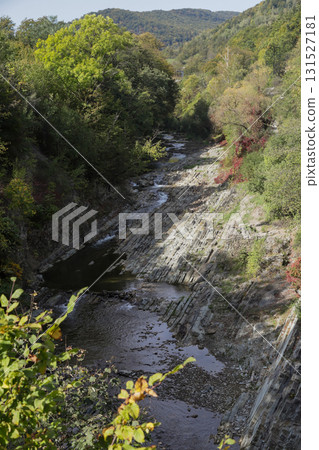 Scenic view of a river valley surrounded by greenery, with rocky terrain and a small wooden structure nestled on the bank Scenic view of a river valley surrounded by greenery, with rocky terrain and a small wooden structure nestled on the bank 131527181