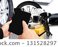 Hands holding digital tablet with black blank screen in front of car spare parts 131528297