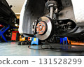 Car brake disc and caliper close up on lifted vehicle in auto repair shop 131528299