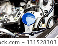 Coolant reservoir tank with blue cap inside car engine bay 131528303