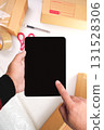 Hands holding digital tablet with black blank screen in parcel packaging workspace 131528306