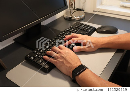 A man touching a computer keyboard, working from home as a side job 131529319