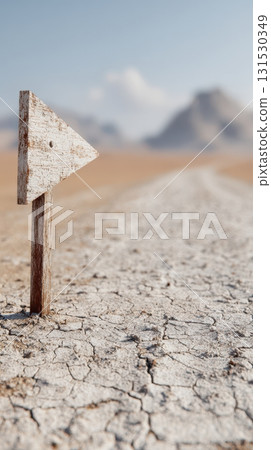 Wooden Arrow Sign On Cracked Desert Ground With Mountains In Background. Symbol Of Direction And Guidance In Barren Landscape 131530349