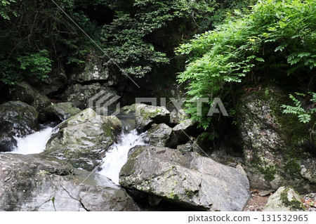 A white waterfall flowing down the black rock face of Hotokebuchi 131532965