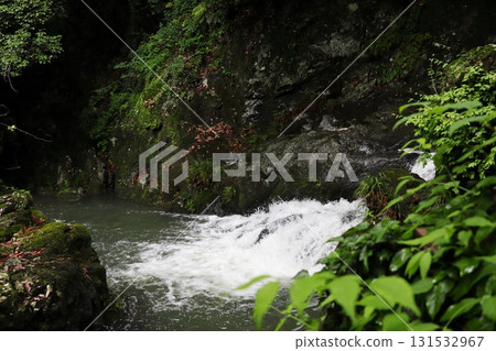 A white waterfall flowing down the black rock face of Hotokebuchi 131532967