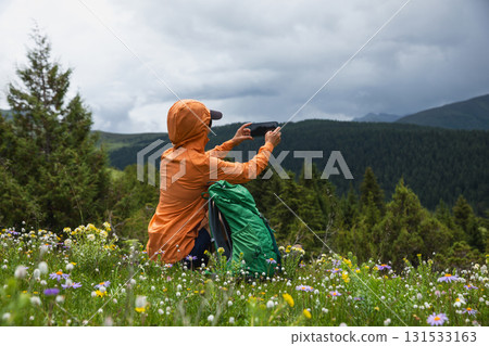 Hiking woman use smartphone taking picture on high altitude forest mountain top 131533163