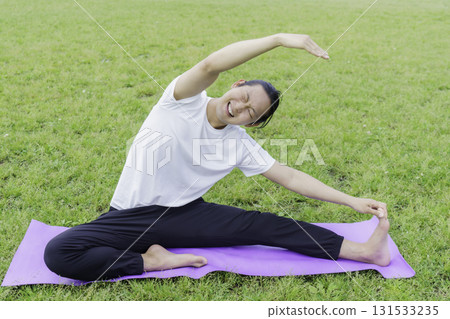 A young man stretching on the grass in a park and looking distressed 131533235