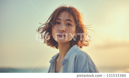 A portrait of a woman standing on the beach at dusk, evoking a sense of sadness and tranquility. 131533360