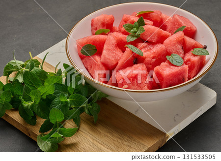 Plate full of diced watermelon garnished with fresh mint. Top view. 131533505