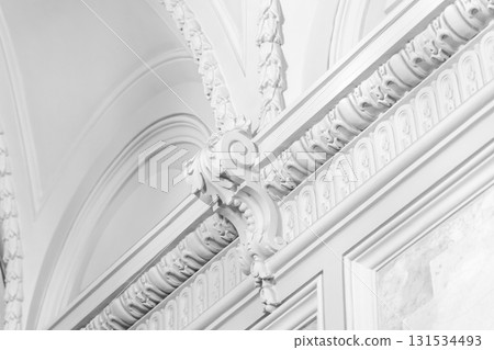 A close-up of a white, ornamental archway with detailed plasterwork A close-up of a white, ornamental archway with detailed plasterwork 131534493