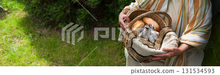 Man holding a basket with fish and bread 131534593
