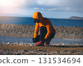 Woman runner tying shoelace at winter lakeside 131534694