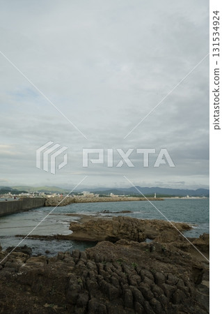 A shallow beach at low tide, with the sea, sky, and clouds visible in the distance 131534924