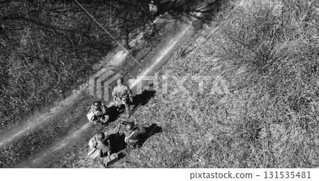 Historical Re-enactment Black And White . Men Dressed As US American Soldiers Of USA Infantry Of World War II sneaking around In spring Autumn Day. Soldiers prepare mortar for battle In dry grass Historical Re-enactment Black And White . Men Dressed As US American Soldiers Of USA Infantry Of World War II sneaking around In spring Autumn Day. Soldiers prepare mortar for battle In dry grass 131535481