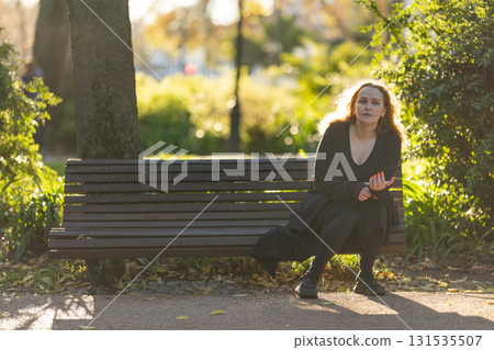 Woman experiencing contemplation while sitting on park bench Woman experiencing contemplation while sitting on park bench 131535507