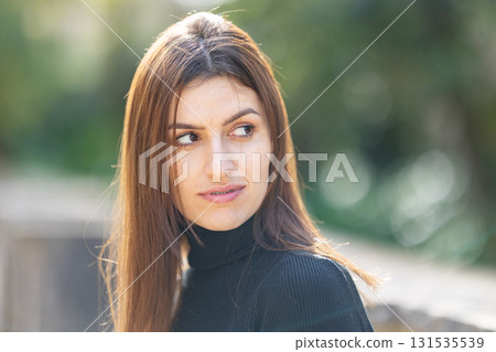 Young woman looking away, feeling thoughtful outdoors 131535539