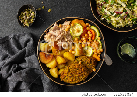 Enjoy a delicious and nutritious breakfast featuring baked sweet potato, colorful vegetables, lentil cutlets, chicken, and a fresh salad 131535854