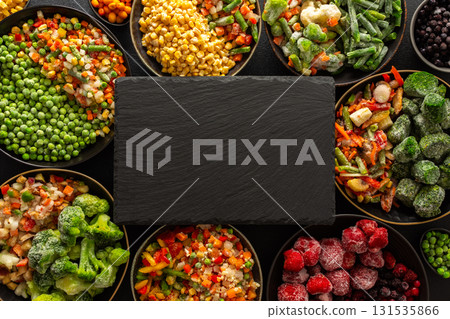 Vibrant seasonal vegetables and fruits frozen for winter storage, displayed on a dark ebonite board, highlighting the fresh, organic harvest ready for future meals and healthy eating 131535866