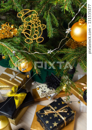 A festive scene featuring gold and black gift boxes, surrounded by shimmering candlelight and stylish decorations under a beautifully decorated Christmas tree, exuding elegance and charm A festive scene featuring gold and black gift boxes, surrounded by shimmering candlelight and stylish decorations under a beautifully decorated Christmas tree, exuding elegance and charm 131535877