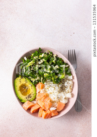 A delightful breakfast charcuterie board showcases creamy avocado, fresh salmon, and vibrant greens arranged in an appealing bowl, perfect for a healthy morning meal 131535964