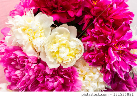 A vibrant arrangement of pink and white peonies showcases their lush petals. This floral display brings energy and beauty to any celebration or home decor setting 131535981