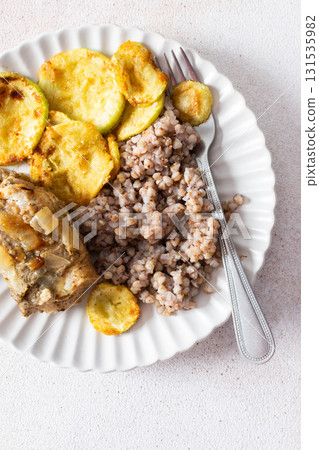 Green buckwheat paired with fried hake, zucchini, and a colorful salad of broccoli, pink radish, and seeds, providing a protein-packed, healthy breakfast to fuel your morning 131535982