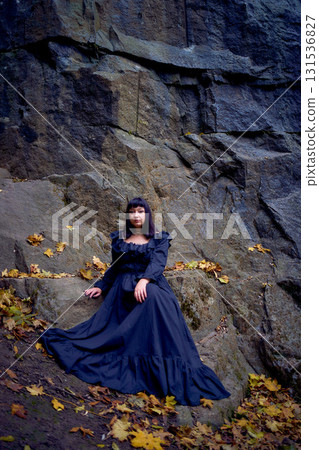 a woman in a black long dress sitting on black rocks on Halloween, modern witch a woman in a black long dress sitting on black rocks on Halloween, modern witch 131536827