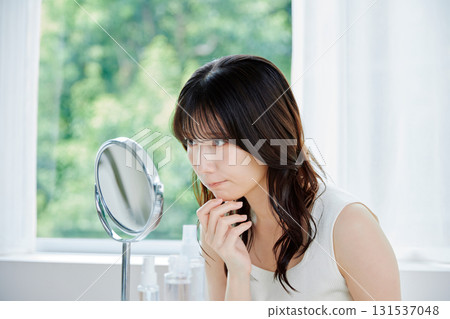 檢查鏡子裡的皮膚狀況的年輕女子 131537048