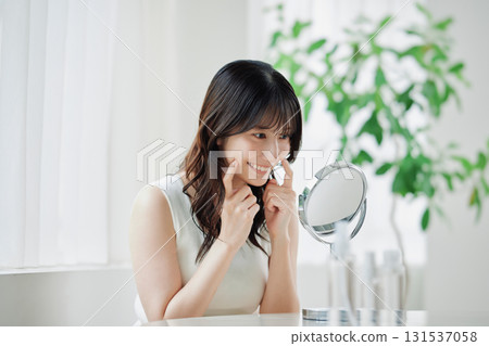 Smiling young woman looking into the mirror Smiling young woman looking into the mirror 131537058