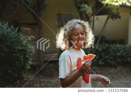 Joyful Child Eating Watermelon in Garden Joyful Child Eating Watermelon in Garden 131537086