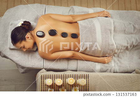 Serene young woman having hot stone massage in spa salon Serene young woman having hot stone massage in spa salon 131537163