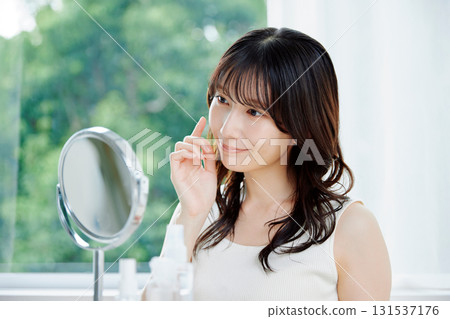 Smiling woman checking her skin condition in the mirror Smiling woman checking her skin condition in the mirror 131537176